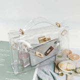 Clear handbag with gold accents on a surface with a magazine and food items.
