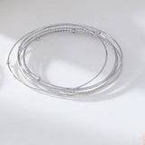 Two circular stainless steel bangle bracelets with a silver and gold color finish on a white background.