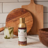 Thymes Frasier Fir diffuser bottle on a marble surface with wooden cutting boards and a glass in the background.