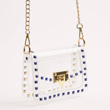 White handbag with gold accents and blue stud details on a white background