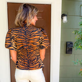 Woman wearing a tiger print top standing in front of a door.