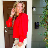 Woman in a red jacket standing outside a house