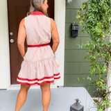 Woman in a red and white dress standing on a porch.