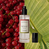 Votivo Red Currant perfume bottle with red currants and a green leaf in the background