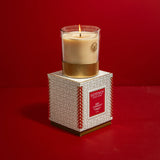 Votivo candle on its packaging against a red background