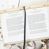 Open book with text on a decorative surface with plants and flowers