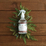 Fruity Fir diffuser bottle with greenery on a wooden background
