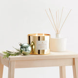 Gold candle with decorative elements on a wooden table against a white background