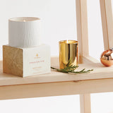 Gold candle and white candle with packaging on a wooden surface