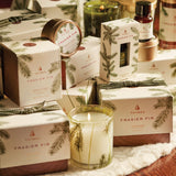 Thymes Frasier Fir candles and packaging on a decorative surface with greenery.
