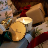 Fragrant candle labeled 'Frasier Fir' with Christmas-themed packaging in the background
