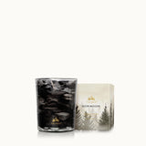 Two candles with forest-themed designs on a white background