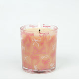 Candle in a glass jar with pink and white bow pattern on a white background
