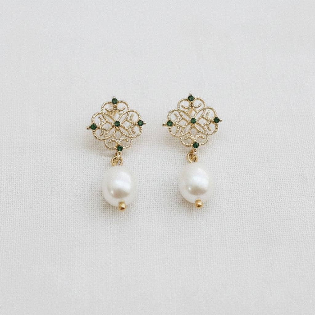 Pair of earrings with gold floral designs and pearl drops on a light gray background