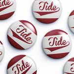 Several round button badges with the word Tide in red script over a white and dark red striped design, arranged on a light gray background.