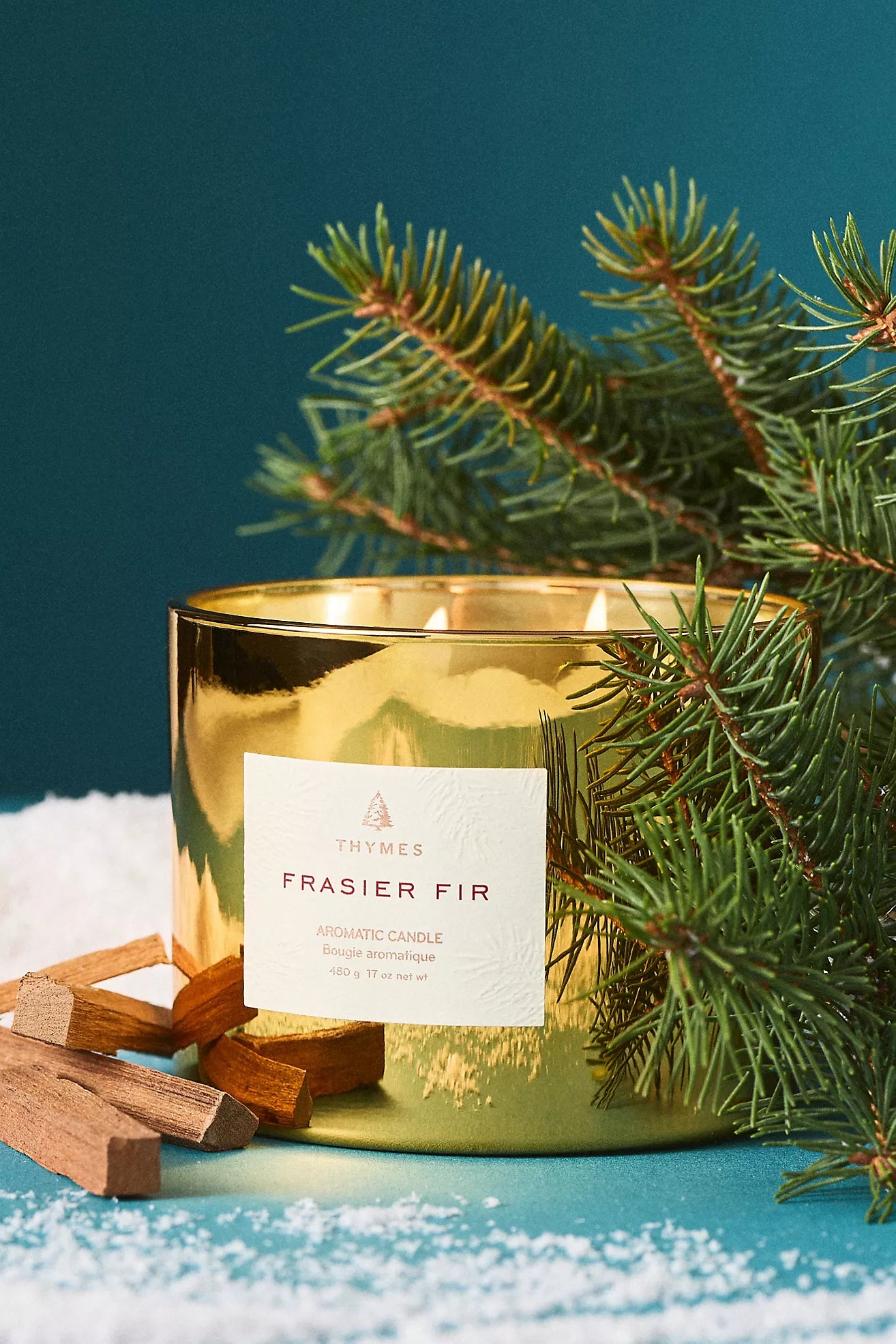 Gold candle labeled 'Frasier Fir' with pine branches on a blue background