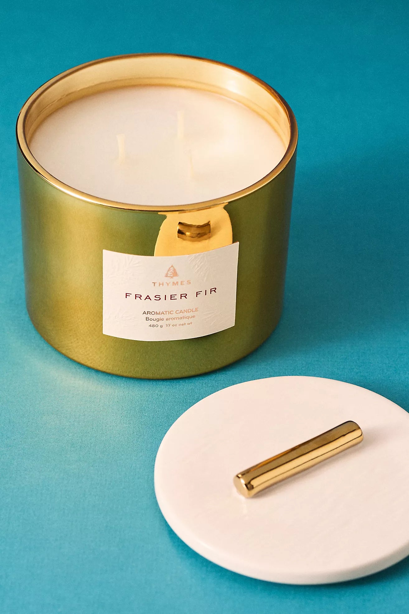 Green candle with gold lid on a blue background