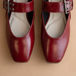Pair of red shoes with buckles on a beige background