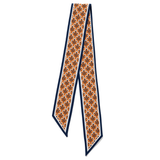 A patterned silk necktie with a repeating fleur-de-lis motif in orange, brown, and black, bordered by navy blue and white stripes, shown on a plain white background.