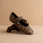 Leopard print shoe with decorative buckle on a beige background
