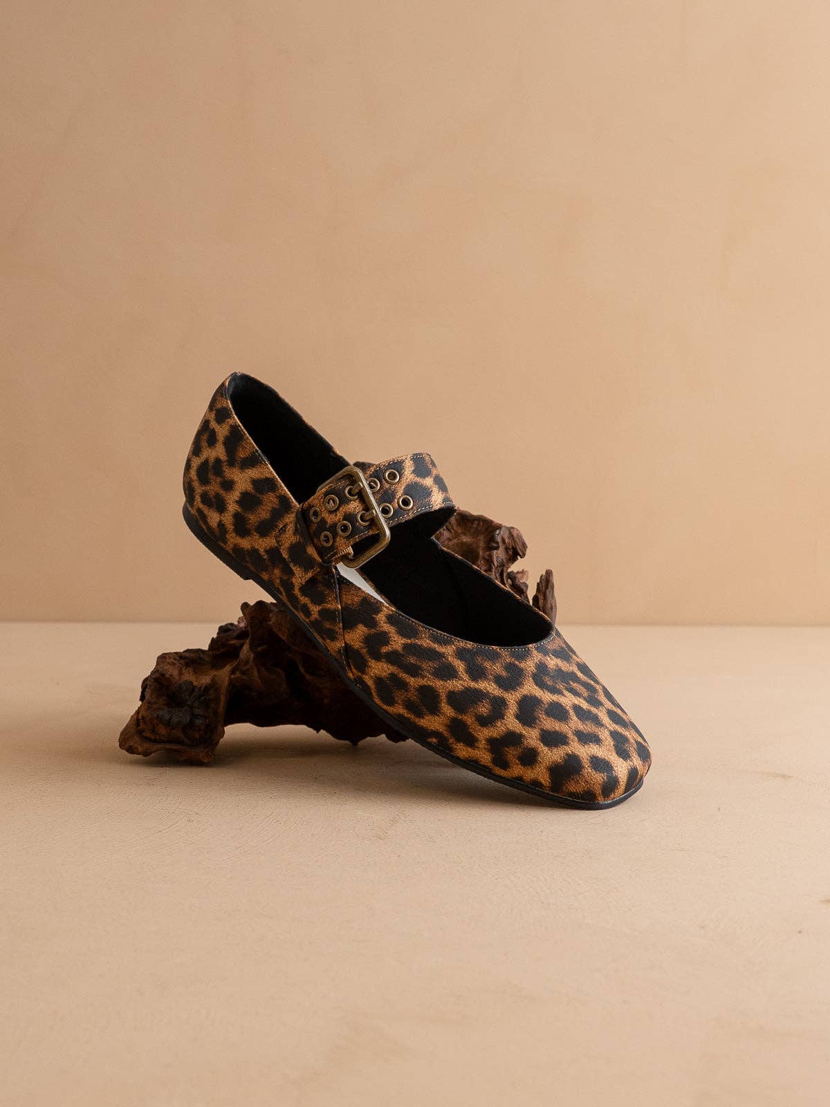 Leopard print shoe with decorative buckle on a beige background