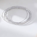 Two circular stainless steel bangle bracelets with a silver and gold color finish on a white background.