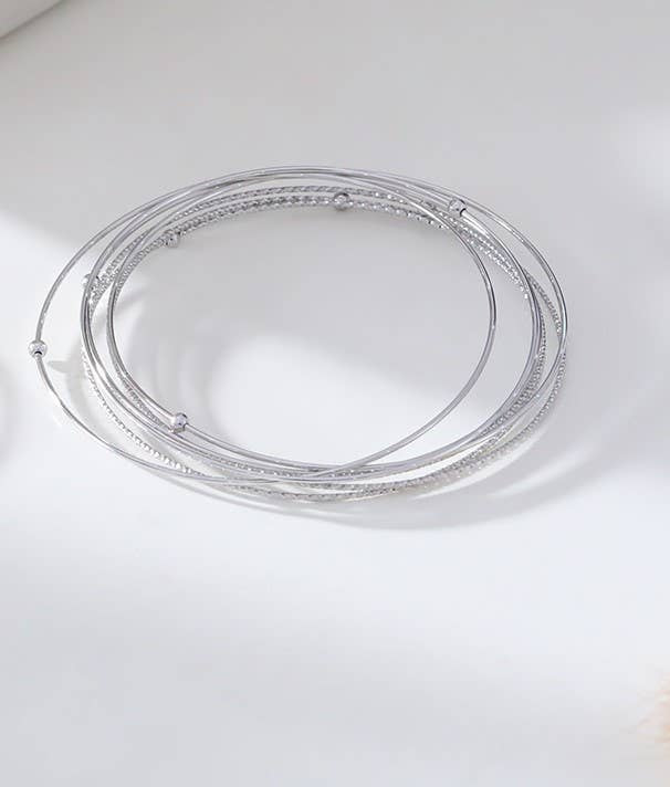 Two circular stainless steel bangle bracelets with a silver and gold color finish on a white background.
