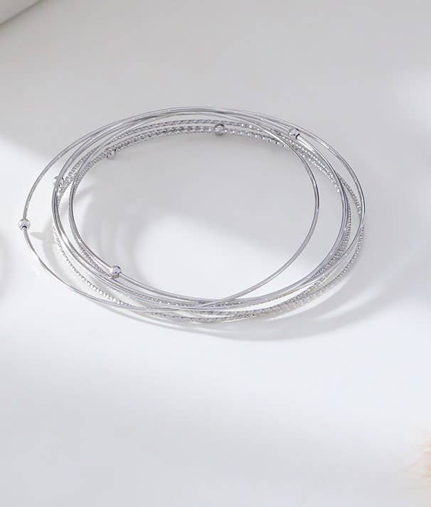Two circular stainless steel bangle bracelets with a silver and gold color finish on a white background.