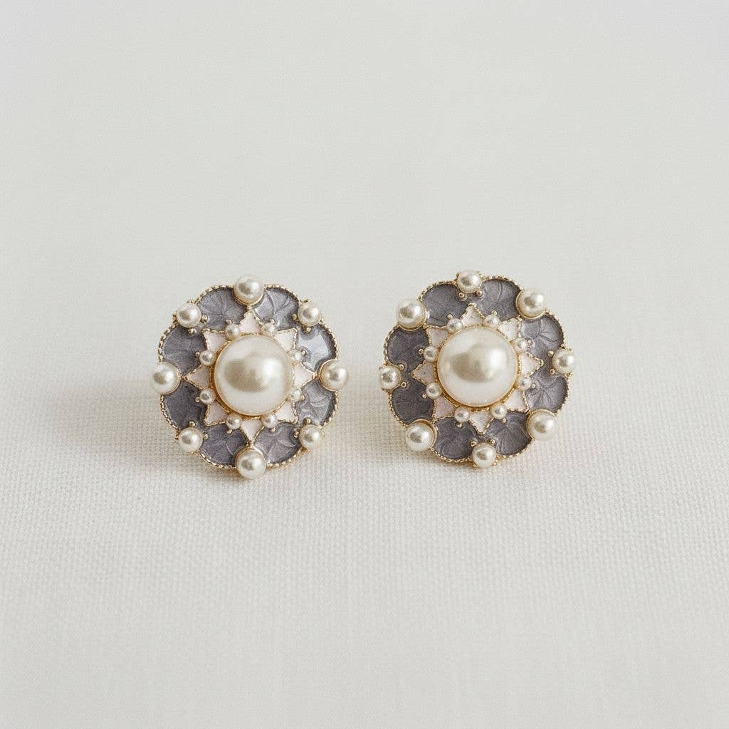 Pair of earrings with pearl center and decorative gray border on a light gray background