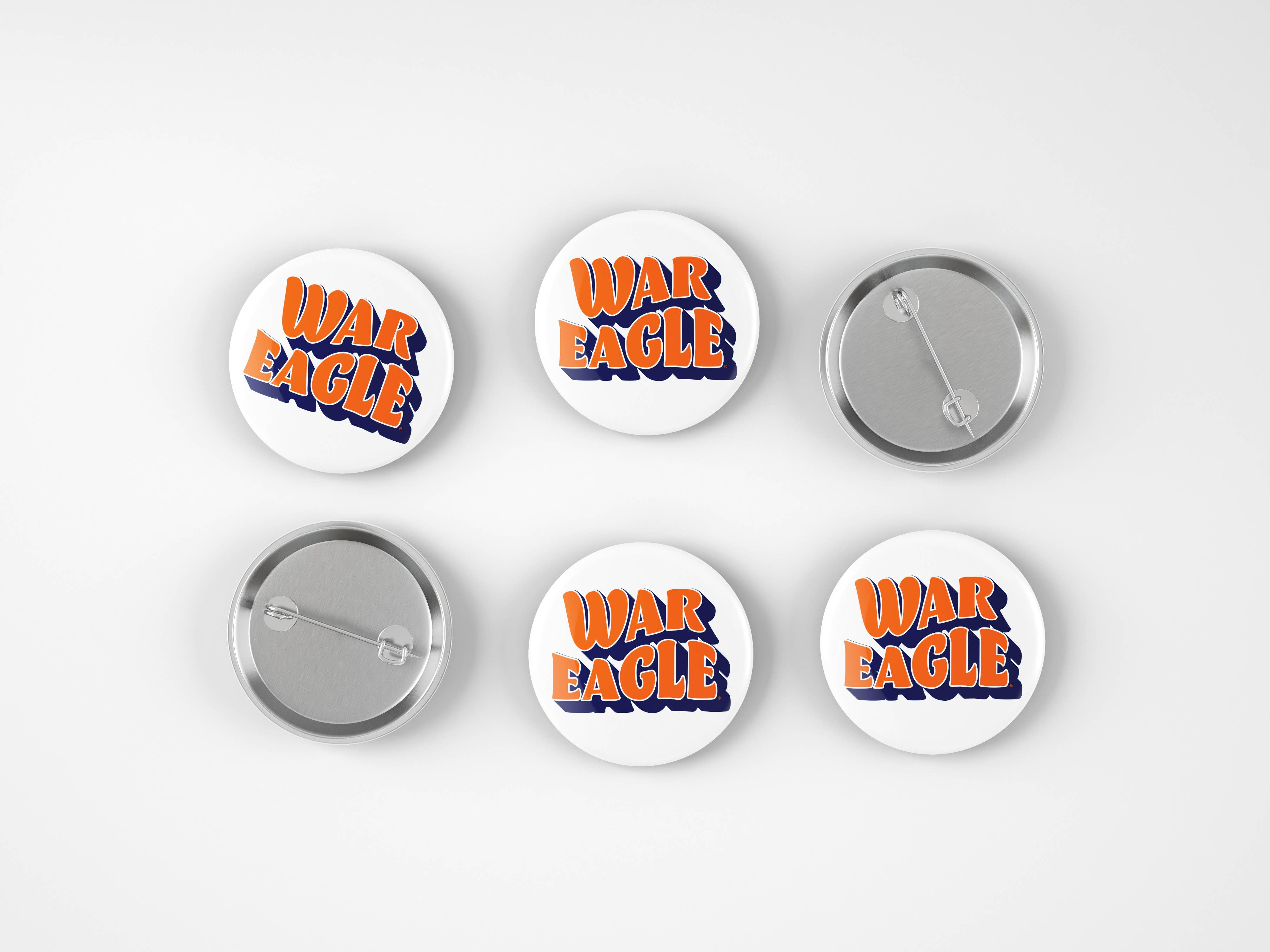 Six round pin-back buttons on a light gray background, showing both the front and back views. The front buttons feature the words 'WAR EAGLE' in orange with a blue outline, while the back buttons show the silver metal pin mechanism.