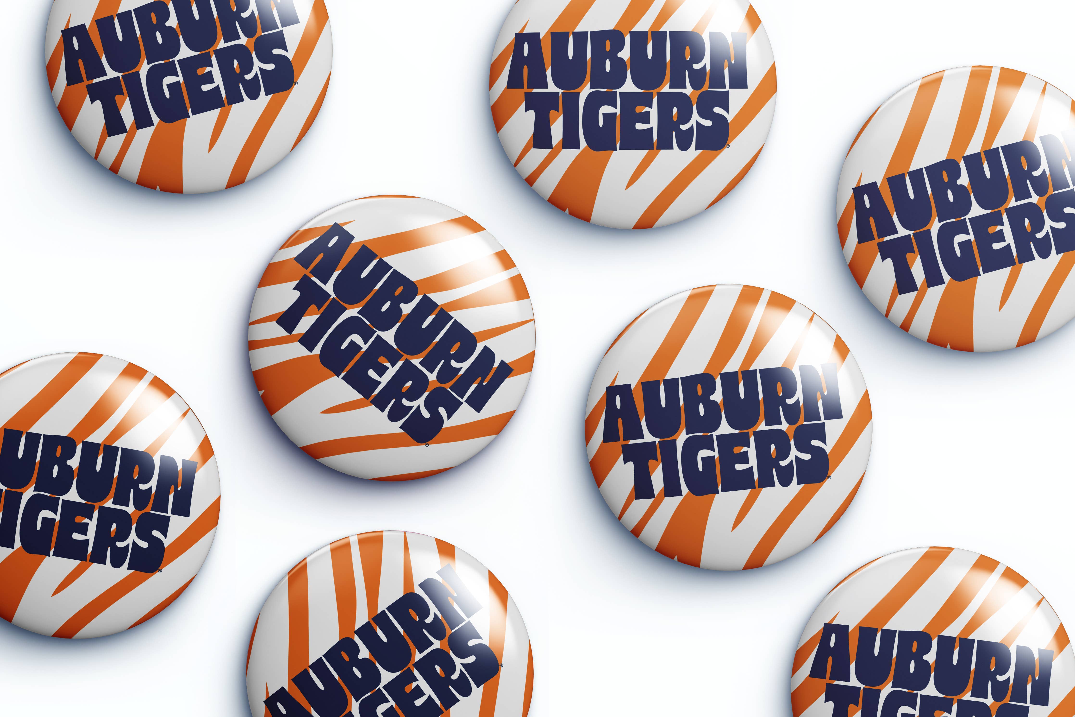 Several round button badges with the Auburn Tigers logo, featuring orange and white tiger stripes and navy blue lettering, arranged on a white background.