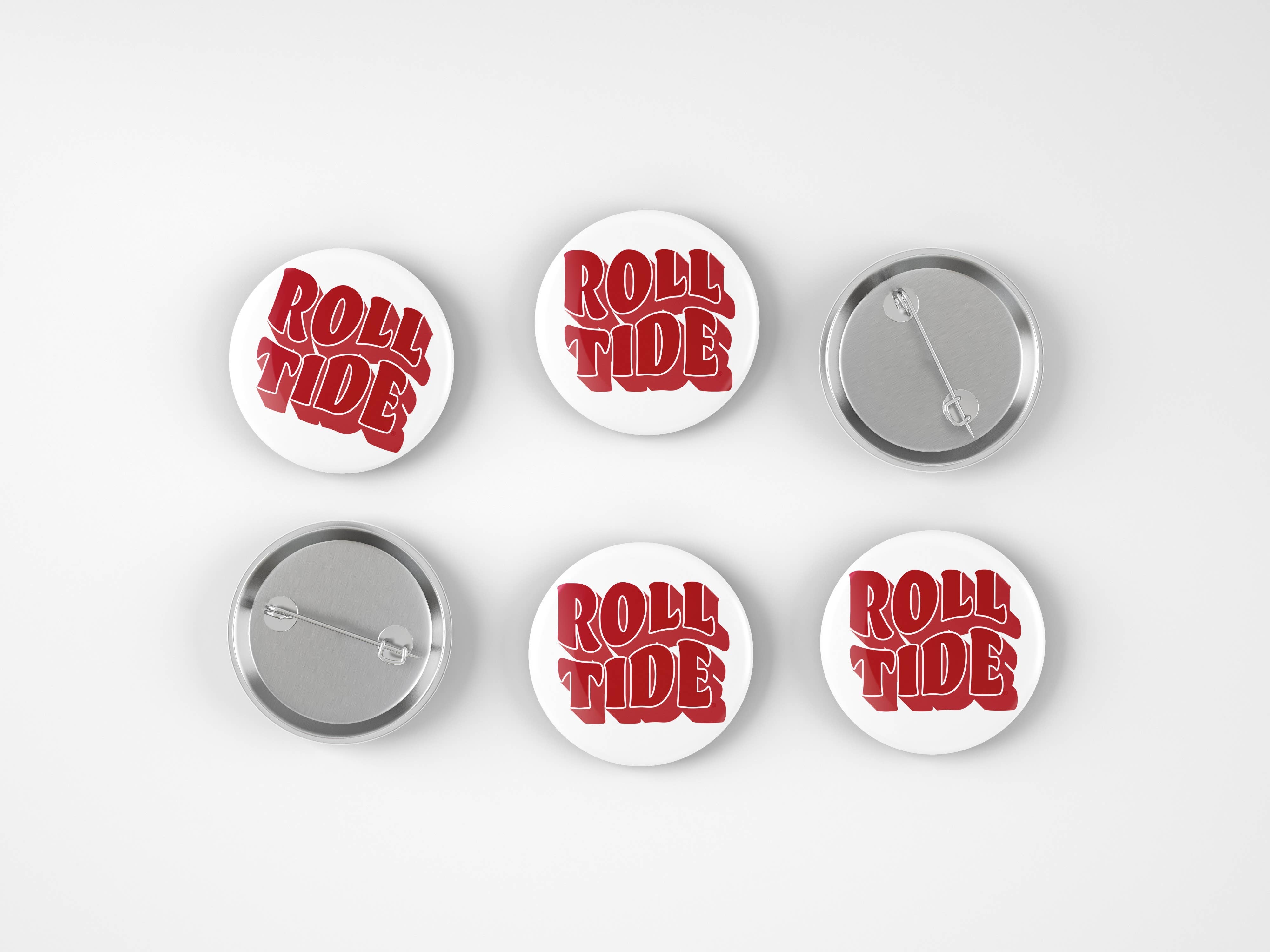 Six round pin-back buttons on a light gray background, showing both the front and back views. The front features the words 'ROLL TIDE' in red 3D-style lettering on a white background, while the backs show a silver metal clasp.