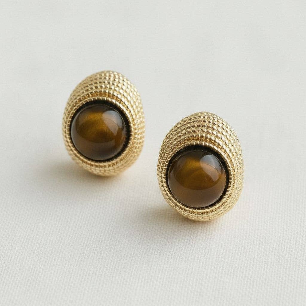 Gold earrings with brown gemstones on a light gray background
