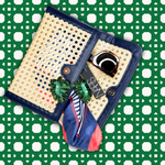 Decorative clutch with a watch, earrings, and a scarf on a green and white patterned background