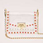 White handbag with gold chain strap and red studded details on a light gray background