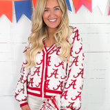 Woman wearing a red and white lettered jacket with colorful flags in the background