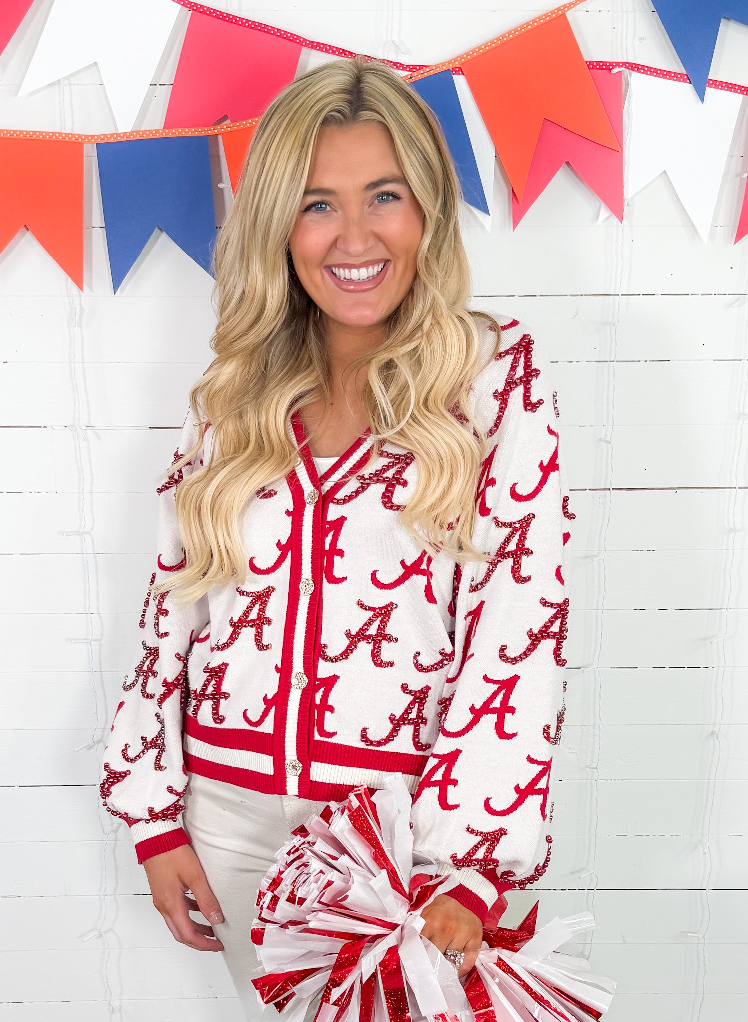 Woman wearing a red and white lettered jacket with colorful flags in the background