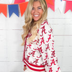 Woman wearing a white jacket with red 'A' pattern in front of colorful flags.