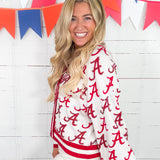 Woman wearing a white jacket with red 'A' pattern in front of colorful flags.