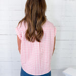 Person wearing a red and white checkered shirt against a white brick wall.