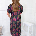 Woman wearing a floral dress against a white wooden panel background