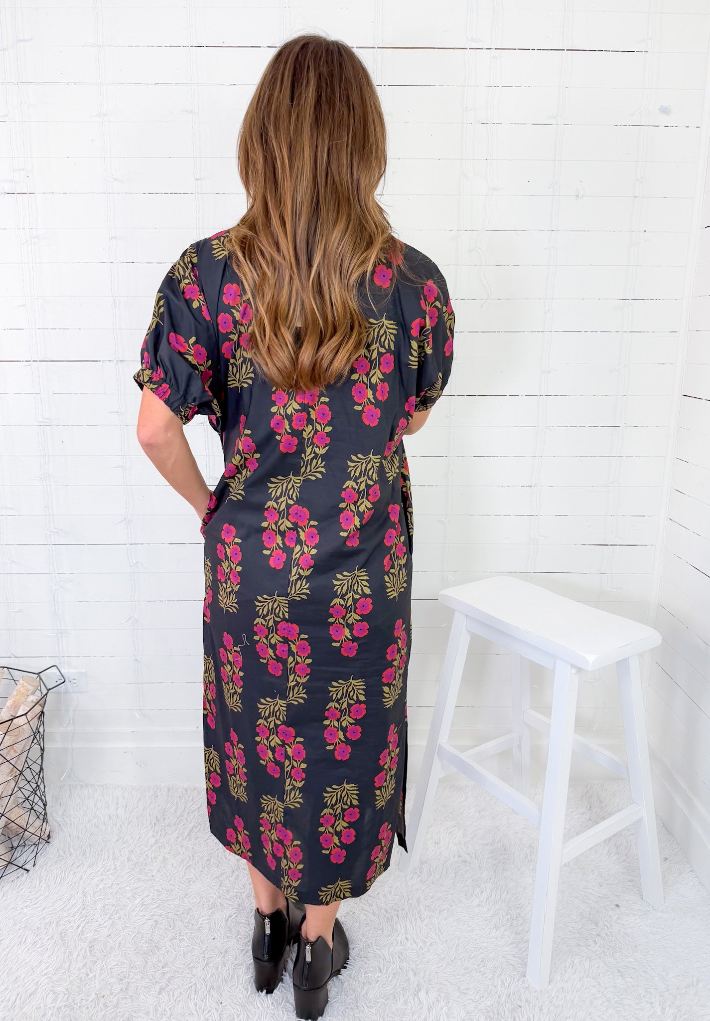 Woman wearing a floral dress against a white wooden panel background