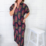 Woman wearing a floral dress standing next to a white stool against a white wooden panel background