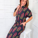 Woman wearing a dark floral dress against a white wooden panel background
