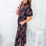 Woman wearing a navy floral dress against a white wooden background