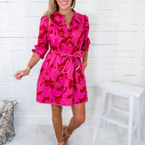 Woman wearing a pink floral dress in a minimal indoor setting