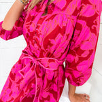 Person wearing a bright pink floral dress on a white background