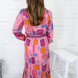 Woman wearing a colorful patterned dress against a white wooden panel background