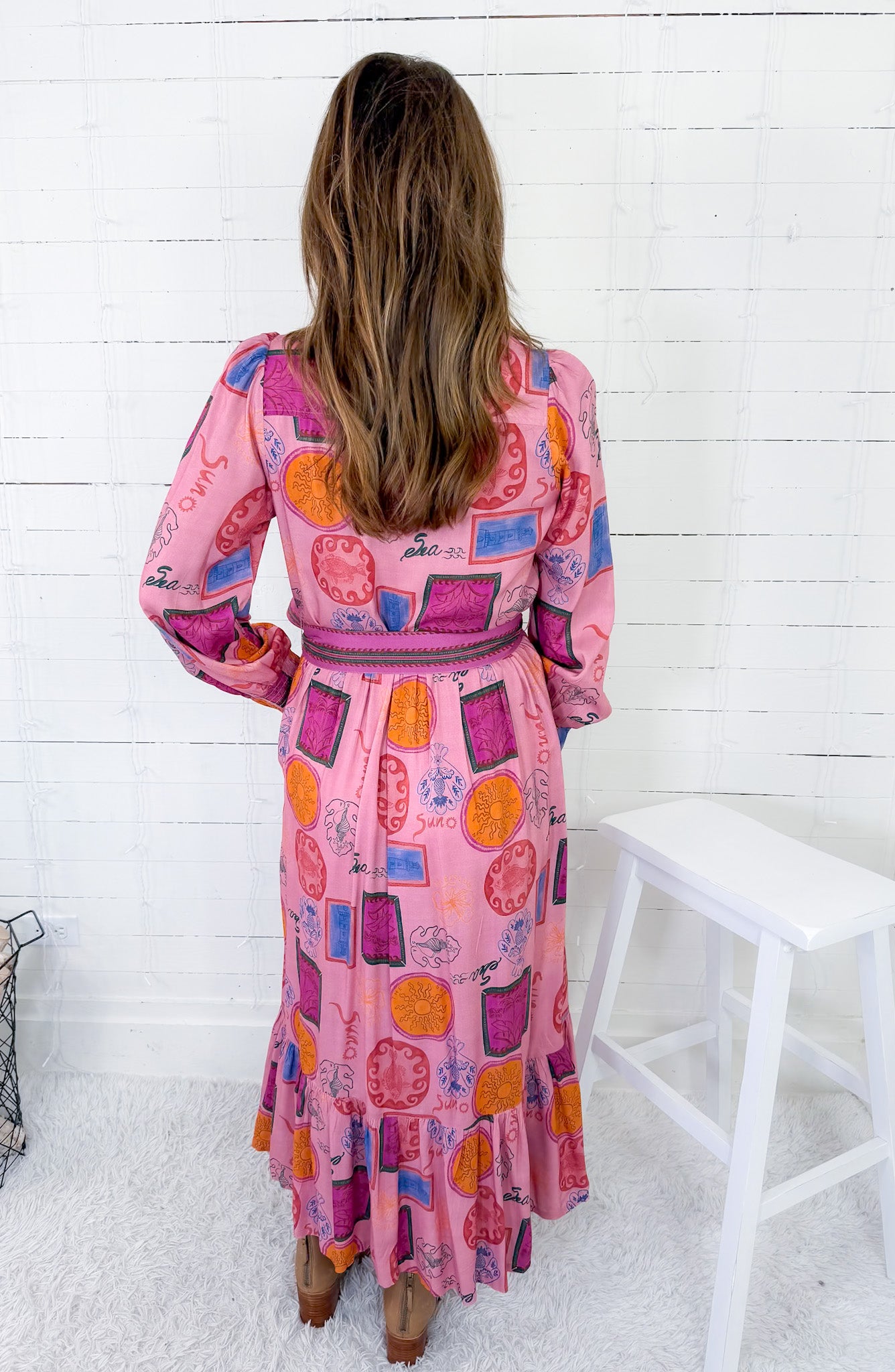Woman wearing a colorful patterned dress against a white wooden panel background