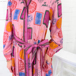 Person wearing a colorful pink dress with abstract patterns on a white background